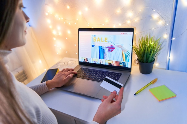 A person making an online credit card payment on a laptop, with a graph showing a downward trend in credit utilization.