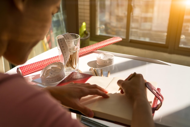Close-up of a woman's hands clipping coupons from a Sunday newspaper, with a cup of coffee and a pair of scissors on the table.