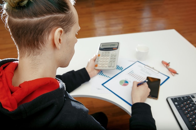 A person calculating their net worth with a calculator and a financial spreadsheet. The focus is on the calculator displaying the result of the calculation.