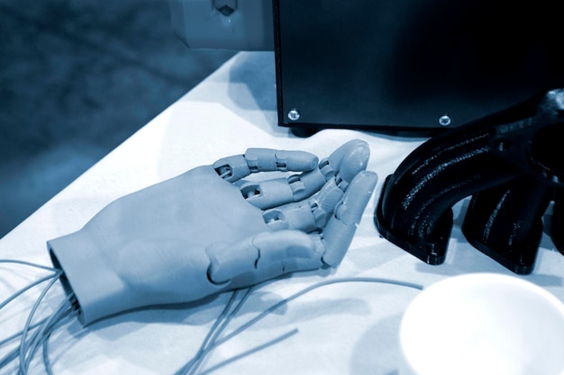 A photo of a 3D printer creating a prosthetic hand in a workshop or lab setting. Show the intricate details of the printing process and the layering of materials. Focus on the precision and technology involved.