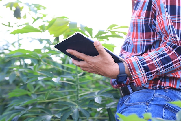 A farmer using a tablet to monitor and control a smart irrigation system in a field. The tablet displays real-time data on water usage, soil moisture, and weather conditions. The irrigation system is visible in the background.