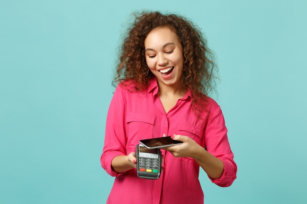 A smartphone displaying a cashback app interface with various store logos and available cashback percentages. The person holding the phone is smiling, indicating satisfaction with the savings.