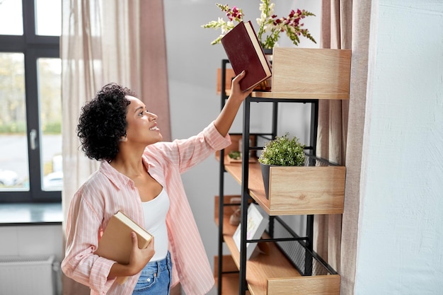 A person holding a book and smiling in natural light. The background shows bookshelf, suggesting a comfortable home environment.