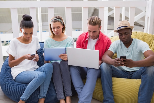 A diverse group of people using various devices (smartphones, tablets, laptops) to access telehealth services. The setting is modern and bright, emphasizing the widespread adoption of technology in healthcare.