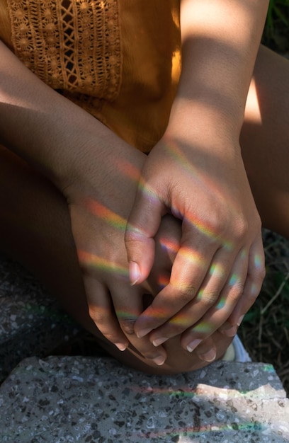 A close-up shot of a person's hands gently resting on their knees in a meditative pose, with soft golden sunlight filtering through the background.