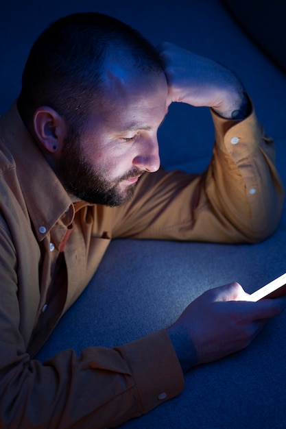 A close-up of a person's face illuminated by a smartphone screen at night, looking stressed and tired, highlighting the negative impact of excessive screen time on sleep and mental health.