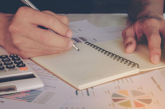 A close-up shot of a hand tracking and categorizing expenses in a notebook, with receipts scattered around, symbolizing the meticulous process of a financial audit.