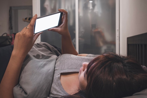 A person reaching for their smartphone first thing in the morning, before even getting out of bed. The scene highlights the immediate and almost involuntary nature of smartphone use upon waking.