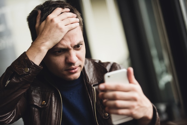 A close-up image of a stressed-out person's face, with a blurred smartphone in the foreground showing multiple notifications. The image highlights the anxiety and overwhelm caused by constant connectivity.